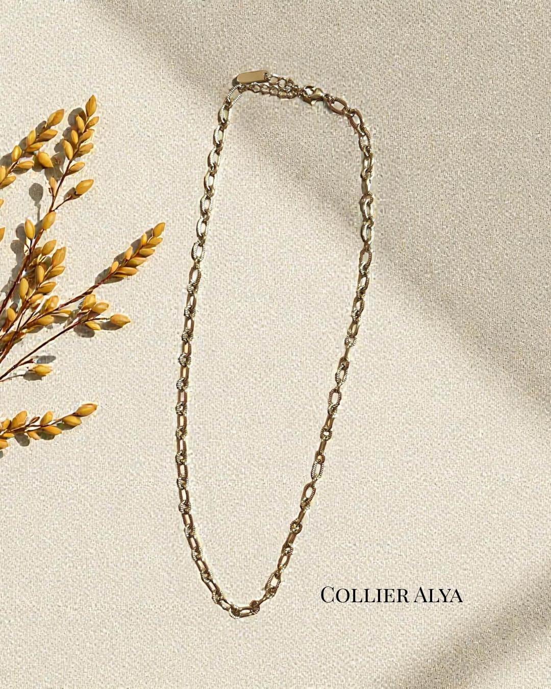 Collier Alya en acier inoxydable doré, maillons fins texturés, longueur 40 cm avec chaînette 3 cm, photographié sur fond crème avec lumière naturelle.