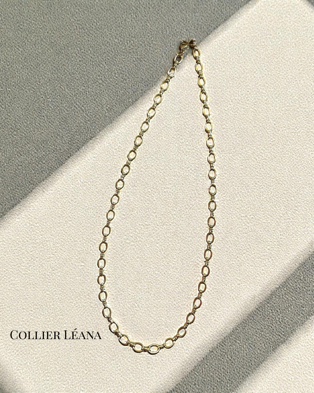 Collier Léana en acier inoxydable doré, maillons ovales texturés, longueur 54 cm, posé sur fond crème en lumière naturelle.