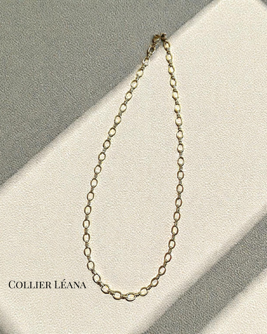 Collier Léana en acier inoxydable doré, maillons ovales texturés, longueur 54 cm, posé sur fond crème en lumière naturelle.