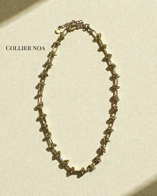 Collier Noa en acier inoxydable doré, maillons torsadés, longueur 45 cm avec chaînette 5 cm, posé sur fond crème.