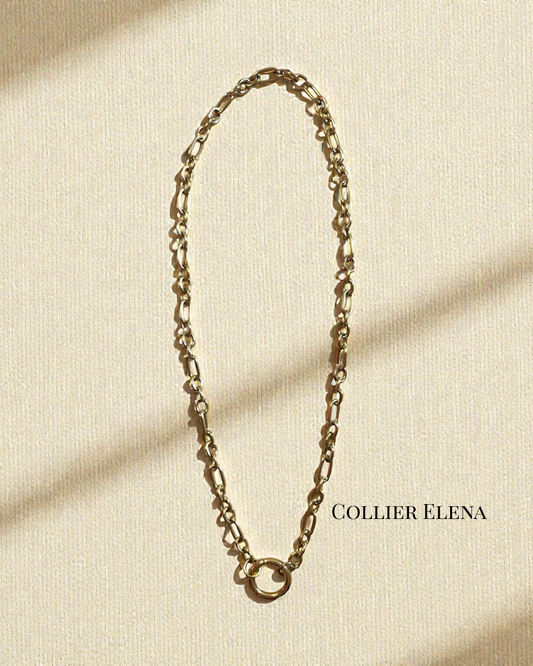 Collier Elena en acier inoxydable doré, chaîne texturée avec grand anneau central, longueur 42 cm, photographié sur fond crème en lumière naturelle.